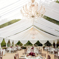 a large tent with tables and chairs and a chandelier