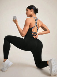 Model in a crisscross back sleeveless active jumpsuit, performing a lunge while holding a dumbbell.