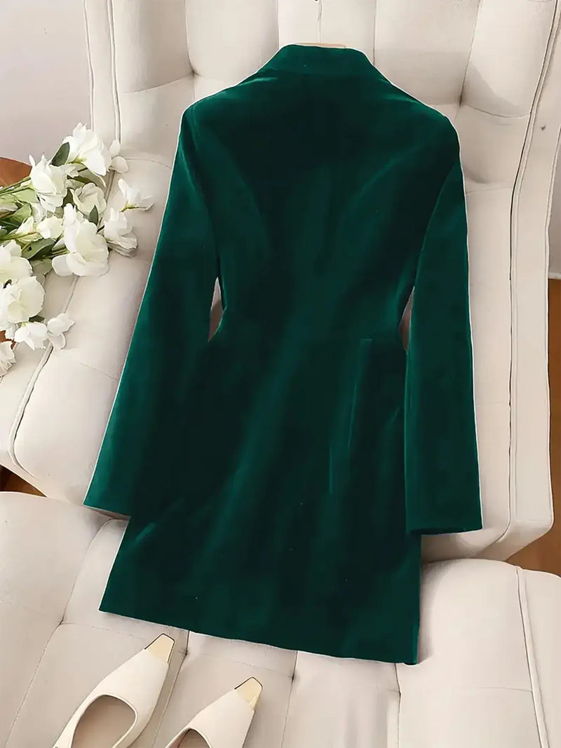 Back view of a luxurious green velvet double-breasted blazer dress on a white armchair, paired with elegant shoes.