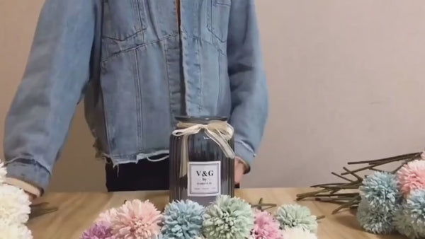 a person standing behind a table with a bottle of wine and pom poms