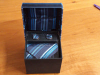 a tie and cufflinks in a box on a table