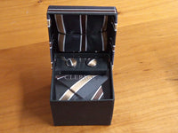 a tie and cufflinks in a box on a table